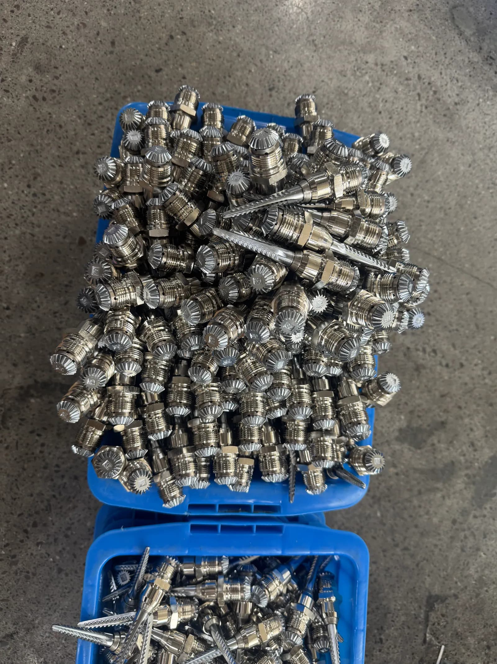 Real factory batches of cotton picker spindle parts in blue reusable bins