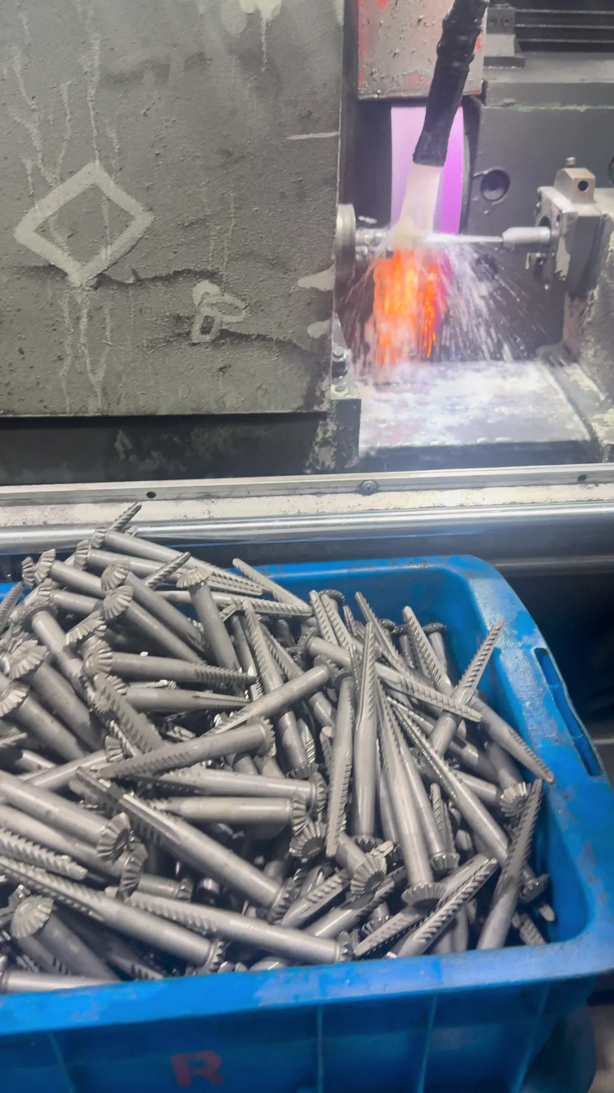 Cotton picker spindles beside an active machining operation with visible sparks