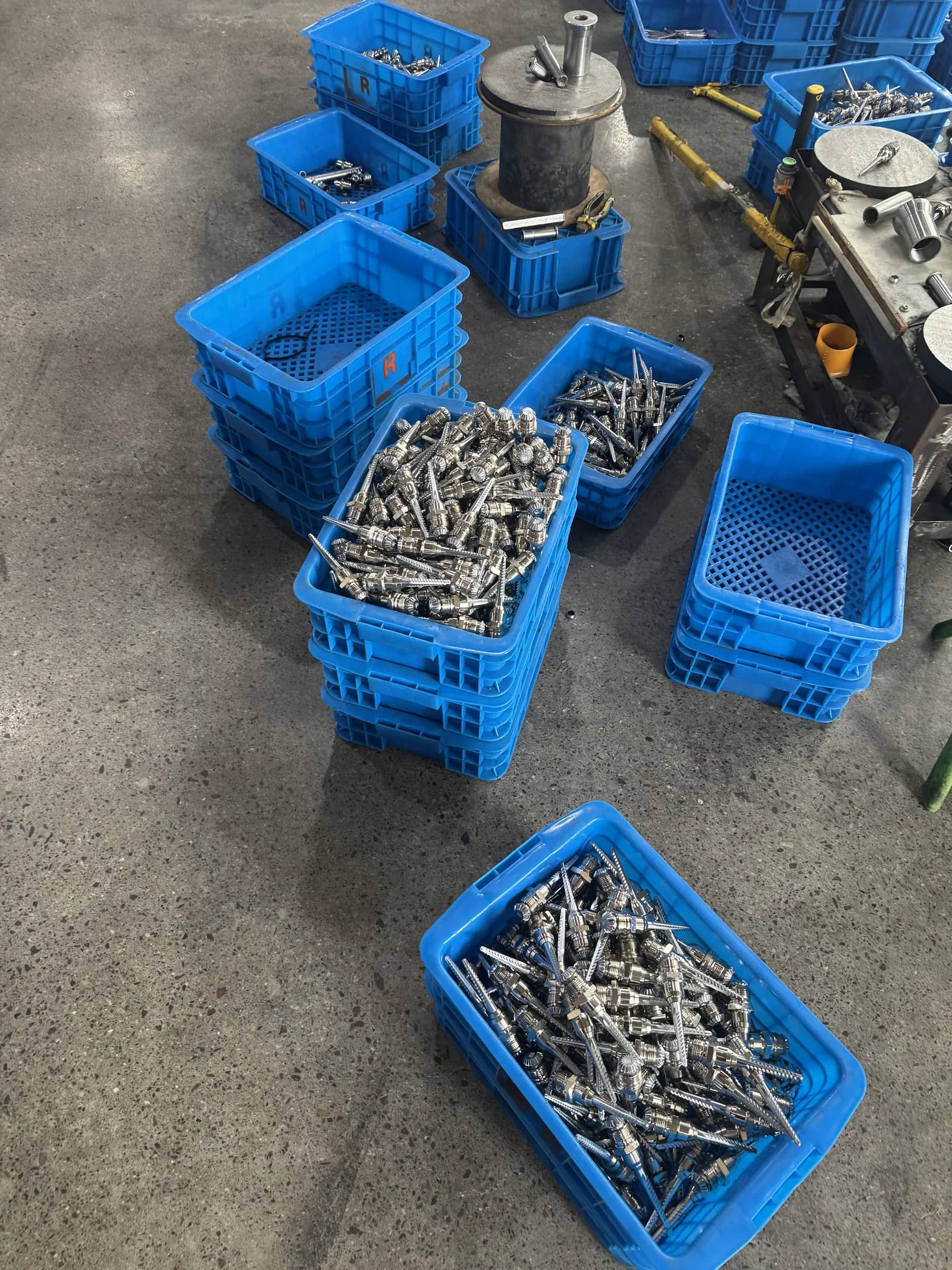 Real factory floor with cotton picker spindle parts separated in blue production bins